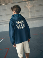 navy blue FC Barcelona hoodie featuring a front zipper and an orange graffiti-style 'FCB' logo printed on the chest