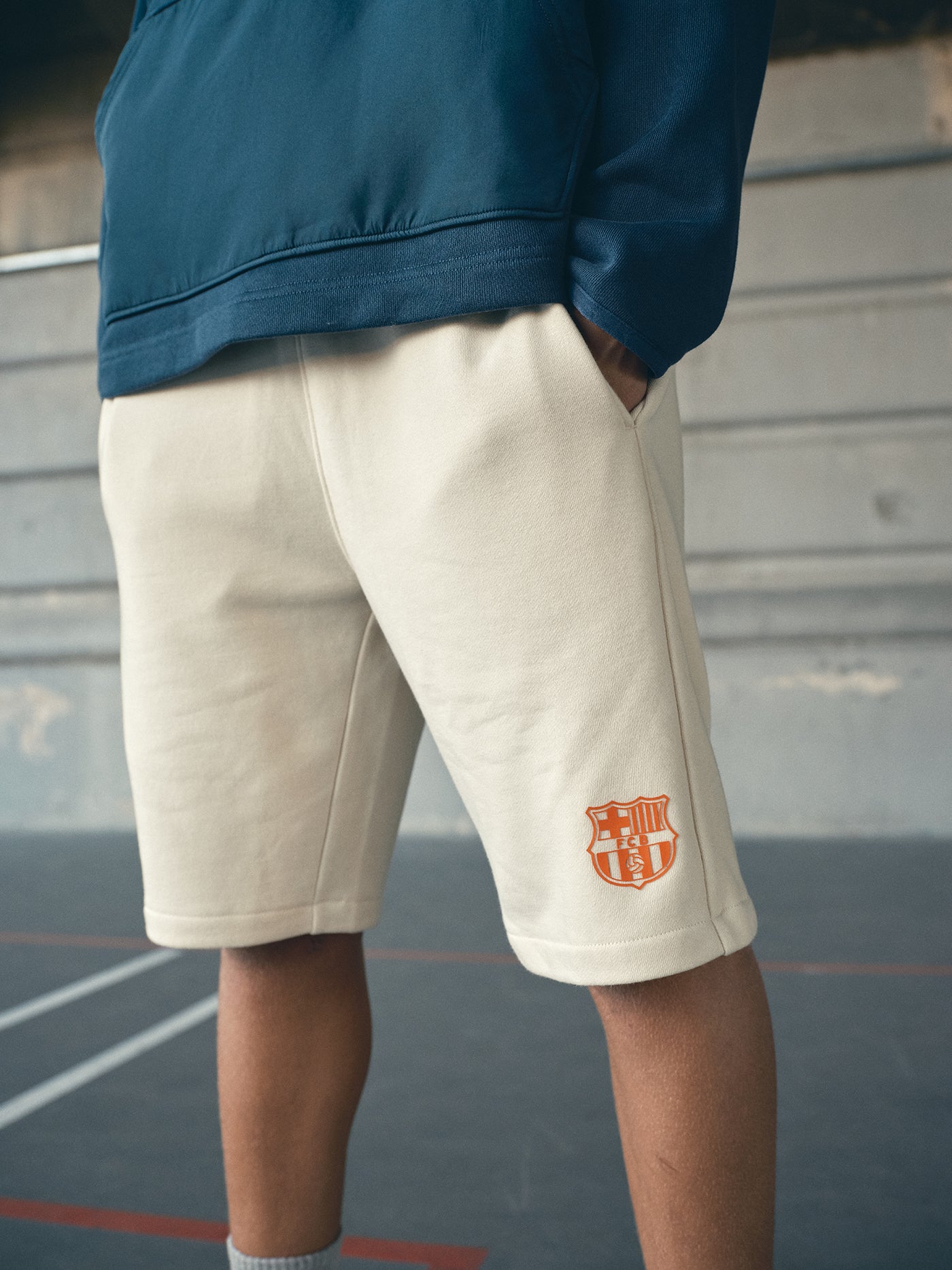beige FC Barcelona shorts featuring the club crest in orange on the left leg