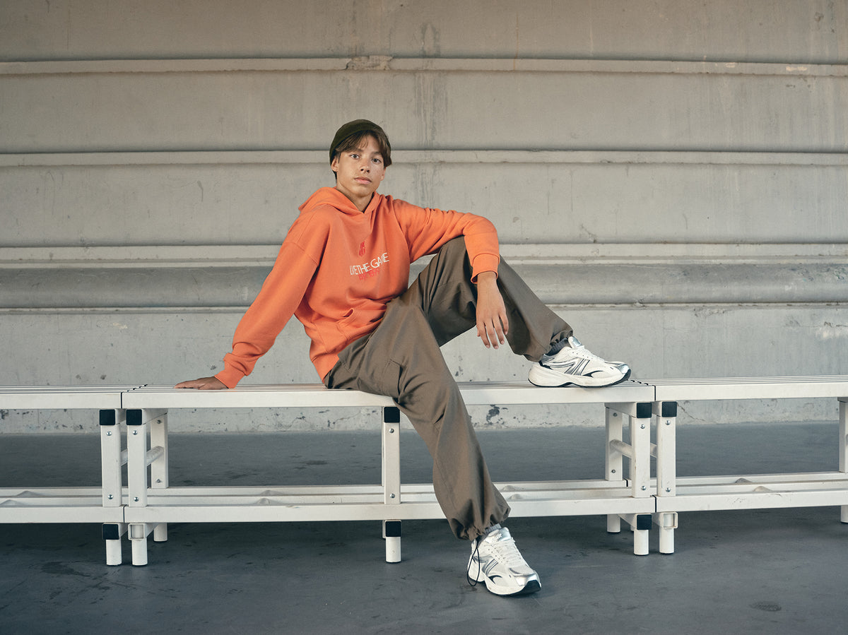 Orange FC Barcelona hoodie featuring the club crest and the slogan 'Live the Game EST. 1899' printed on the front.