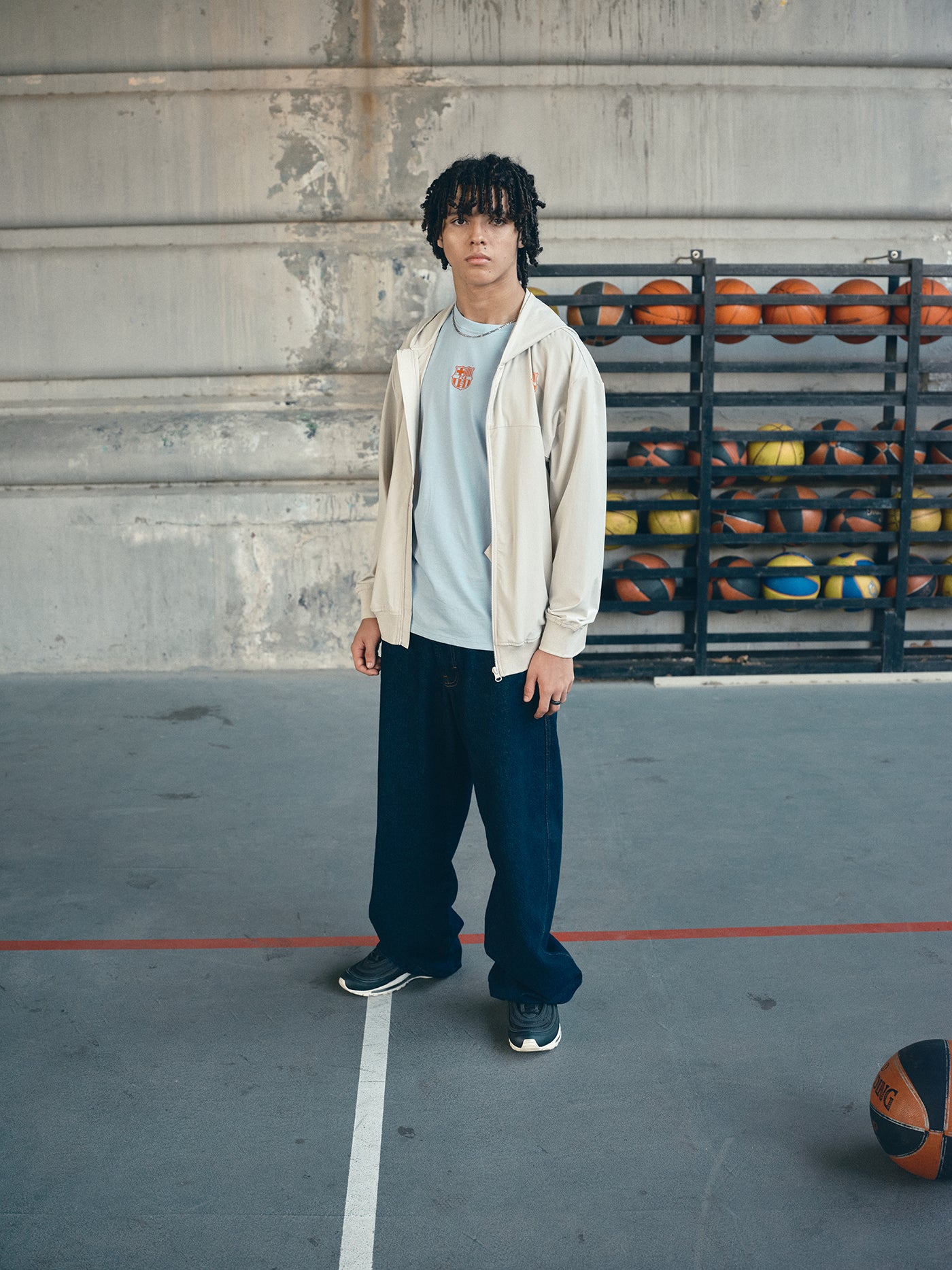 Beige FC Barcelona hooded jacket with minimalist orange graphic icons and text printed across the upper back.