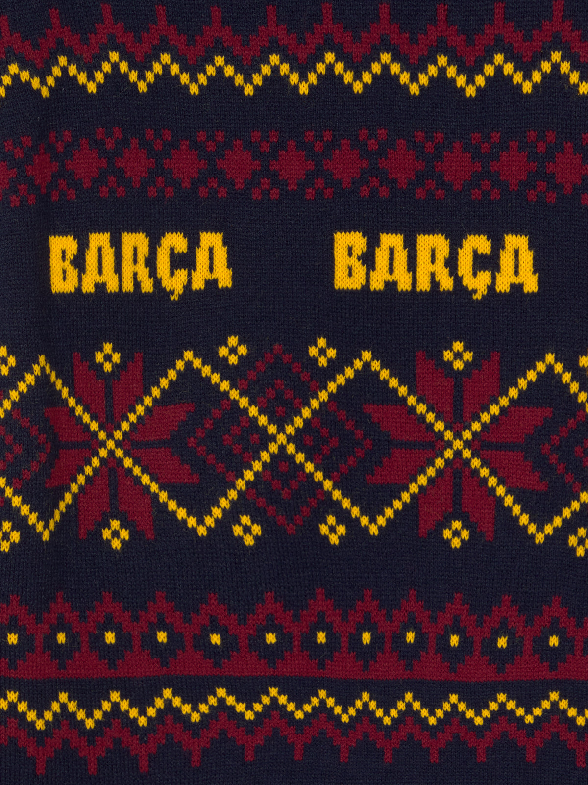 Primer plano de un tejido de punto azul marino con el texto Barça amarillo repetido y patrones geométricos rojos y dorados.