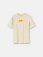 Beige FC Barcelona T-shirt featuring a vibrant vintage-style back print with the word "Barça" in large retro bubble letters. The graphic includes a football, flags, and stadium elements in bold colors within a shield-like frame. A ribbon below the design reads “Since 1899” and “Més que un club.”