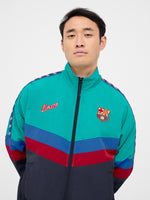 Retro-style windbreaker in teal, red, blue, and navy with FC Barcelona crest and embroidered 'Barça' text on the chest.
