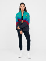 Retro-style windbreaker in teal, red, blue, and navy with FC Barcelona crest and embroidered 'Barça' text on the chest.