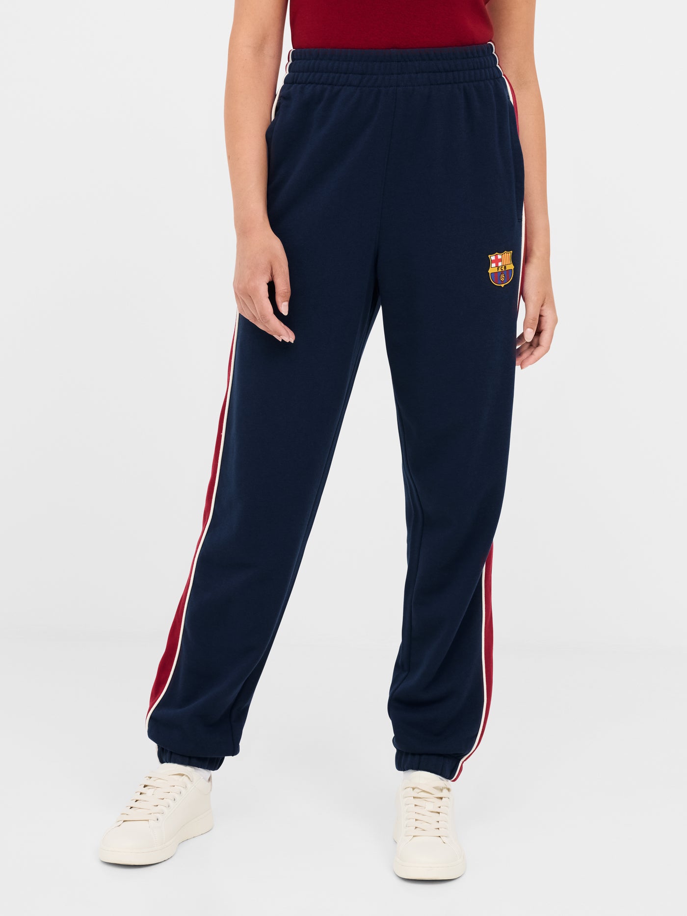 Navy blue FC Barcelona track pants with red side panels and white piping. The pants feature the club crest on the upper left leg and have an elastic waistband and cuffs for a comfortable fit.






