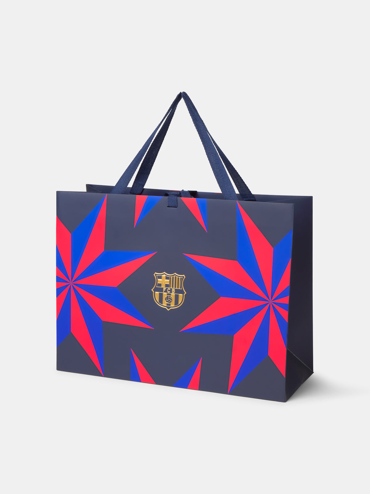 Vista frontal de una bolsa regalo de FC Barcelona azul marino con estampado geométrico rojo y azul y el escudo dorado centrado.
