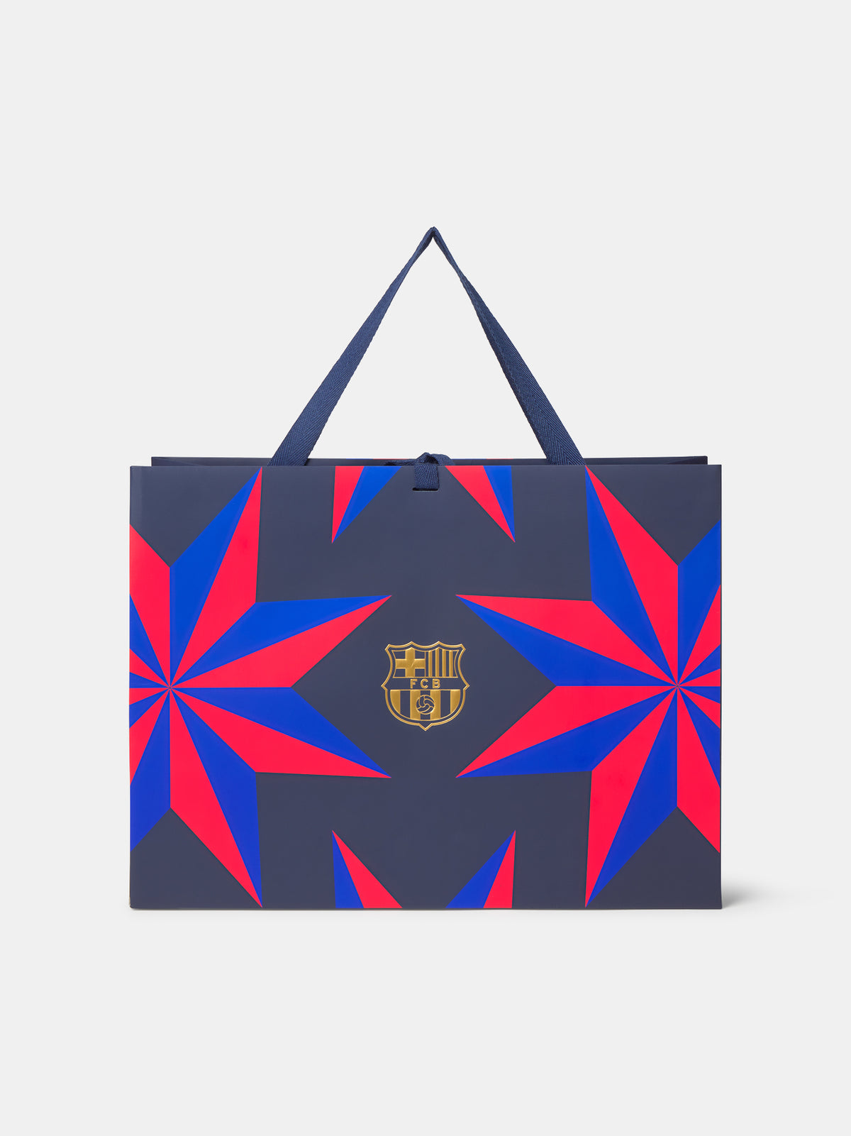Bolsa de regalo de FC Barcelona con fondo azul marino, estampado geométrico de estallidos de estrellas en rojo y azul y escudo dorado del club centrado en el frente.