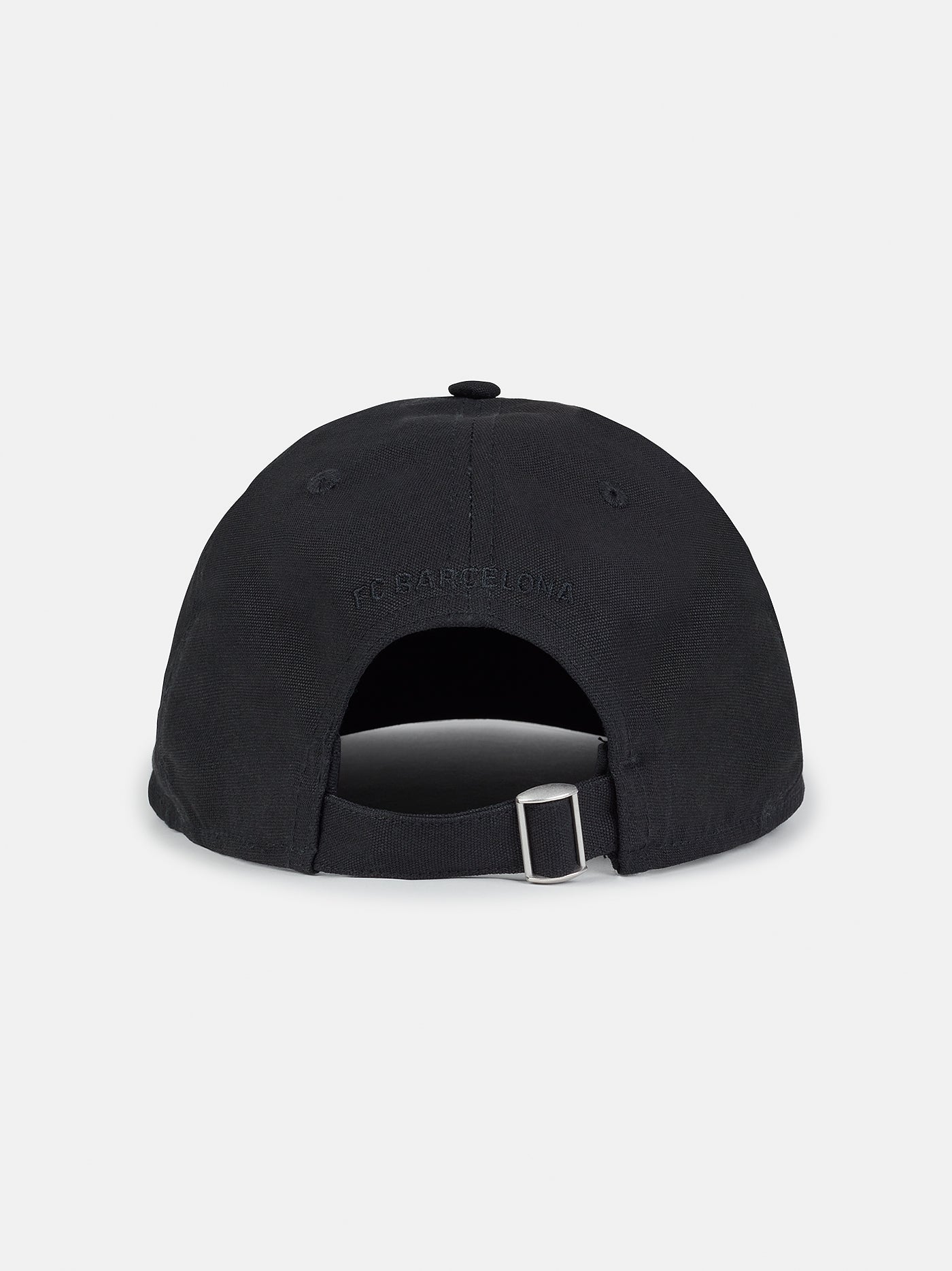 Black flat-brim cap featuring a rectangular white patch on the front with the FC Barcelona crest and the slogan "Més que un club" printed in black.