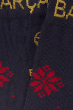 Primer plano de un tejido de punto azul marino con letras amarillas y motivos florales rojos de FC Barcelona.