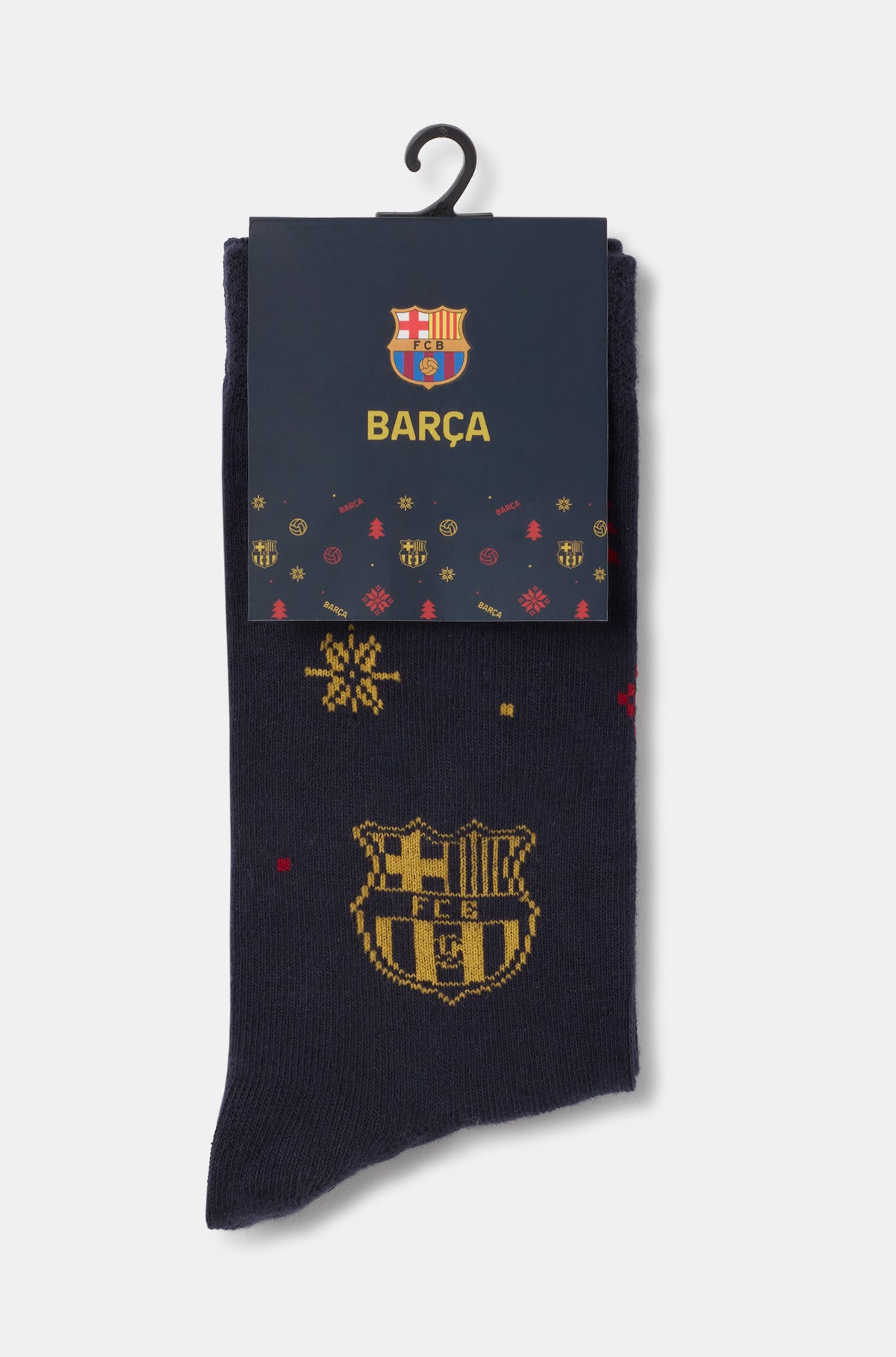 Calcetines azul marino de FC Barcelona en una percha, con escudo Barça dorado y estampado de copos de nieve, parcialmente cubiertos por el embalaje de la marca.