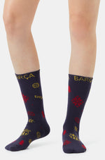 Par de calcetines azul marino de FC Barcelona con lettering Barça amarillo y estampados rojos de invierno, sobre las piernas de un modelo.