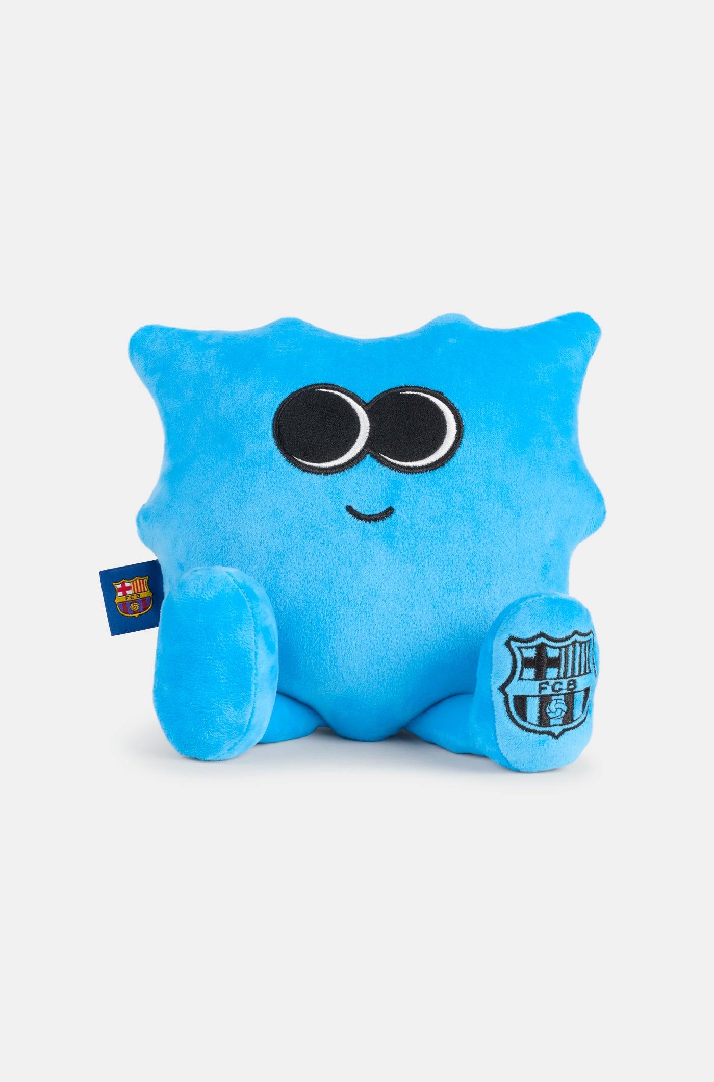 Blue plush toy with big eyes and a small smile, featuring the FC Barcelona crest on one foot and a club tag on the side