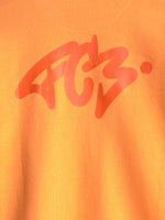 Primer plano de una camiseta naranja del FC Barcelona con un gran gráfico abstracto rojo estampado en el pecho.