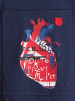 Detail of a navy FC Barcelona garment with a large stylized heart graphic in red, blue and white and a small Barça crest patch near the top right.