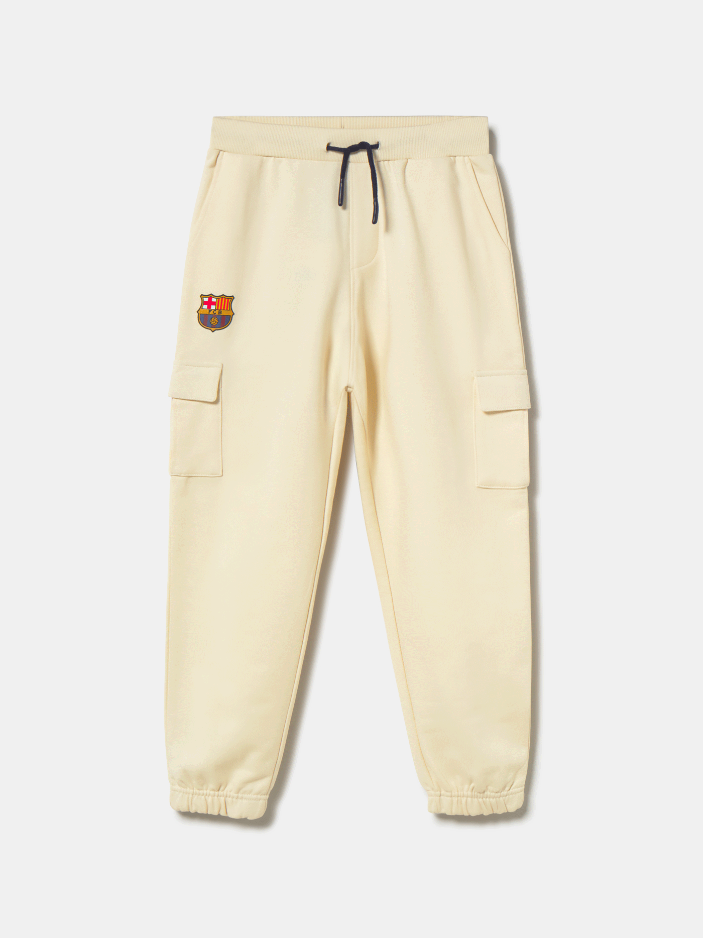 Beige FC Barcelona kids' jogger pants with side cargo pockets, elastic cuffs, drawstring waist, and club crest on the upper leg.
