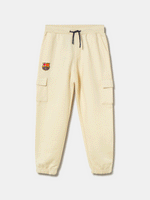 Beige FC Barcelona kids' jogger pants with side cargo pockets, elastic cuffs, drawstring waist, and club crest on the upper leg.