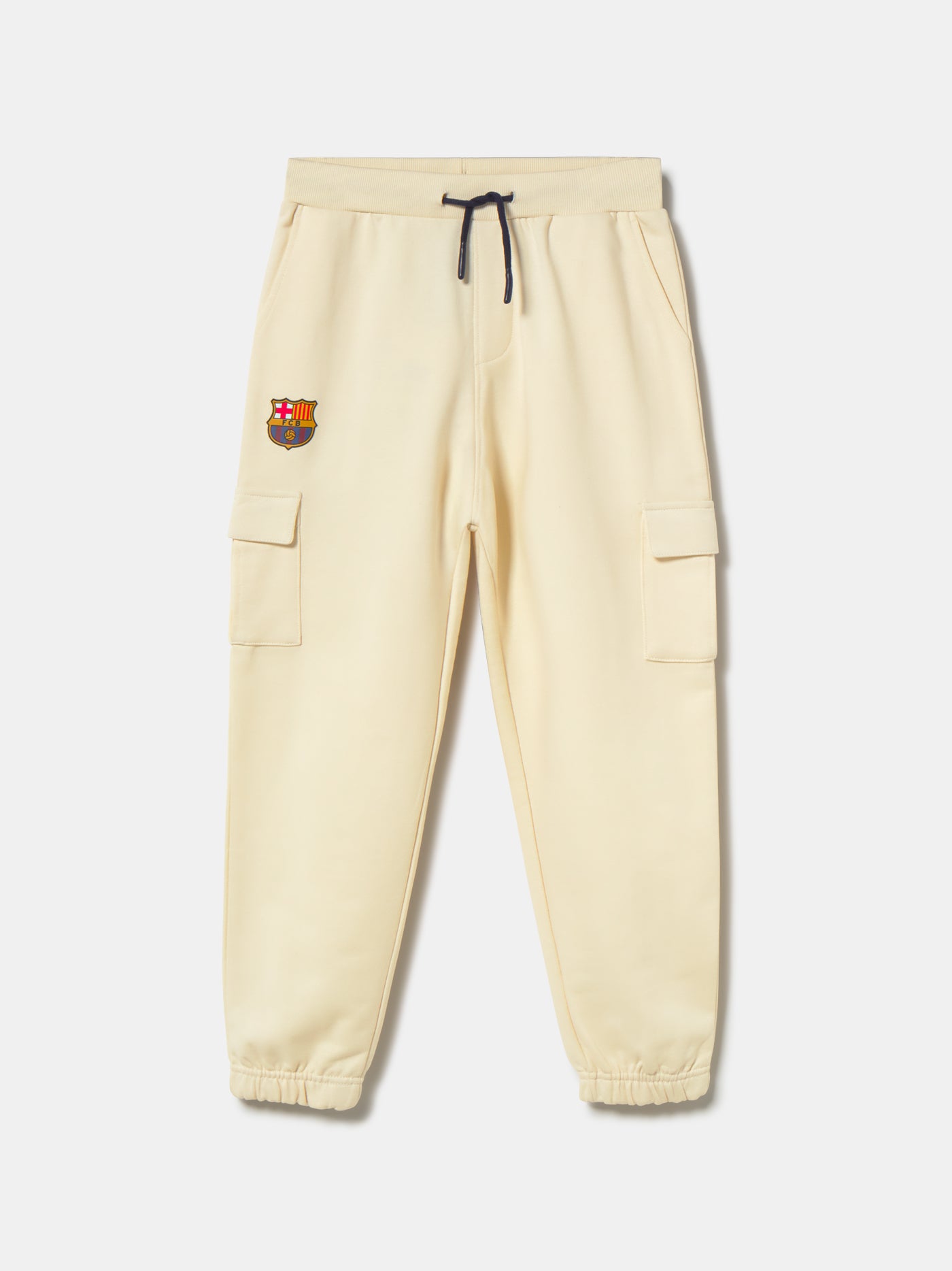 Beige FC Barcelona kids' jogger pants with side cargo pockets, elastic cuffs, drawstring waist, and club crest on the upper leg.