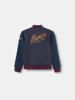 Navy blue FC Barcelona varsity jacket with embroidered 1899 detail, club crest on the chest, and red striped collar, cuffs, and hem.