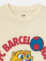 cream FC Barcelona T-shirt featuring the club's name and Cat Culer, the cartoon mascot, playing football.