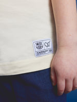 cream FC Barcelona T-shirt featuring the club's name and Cat Culer, the cartoon mascot, playing football.