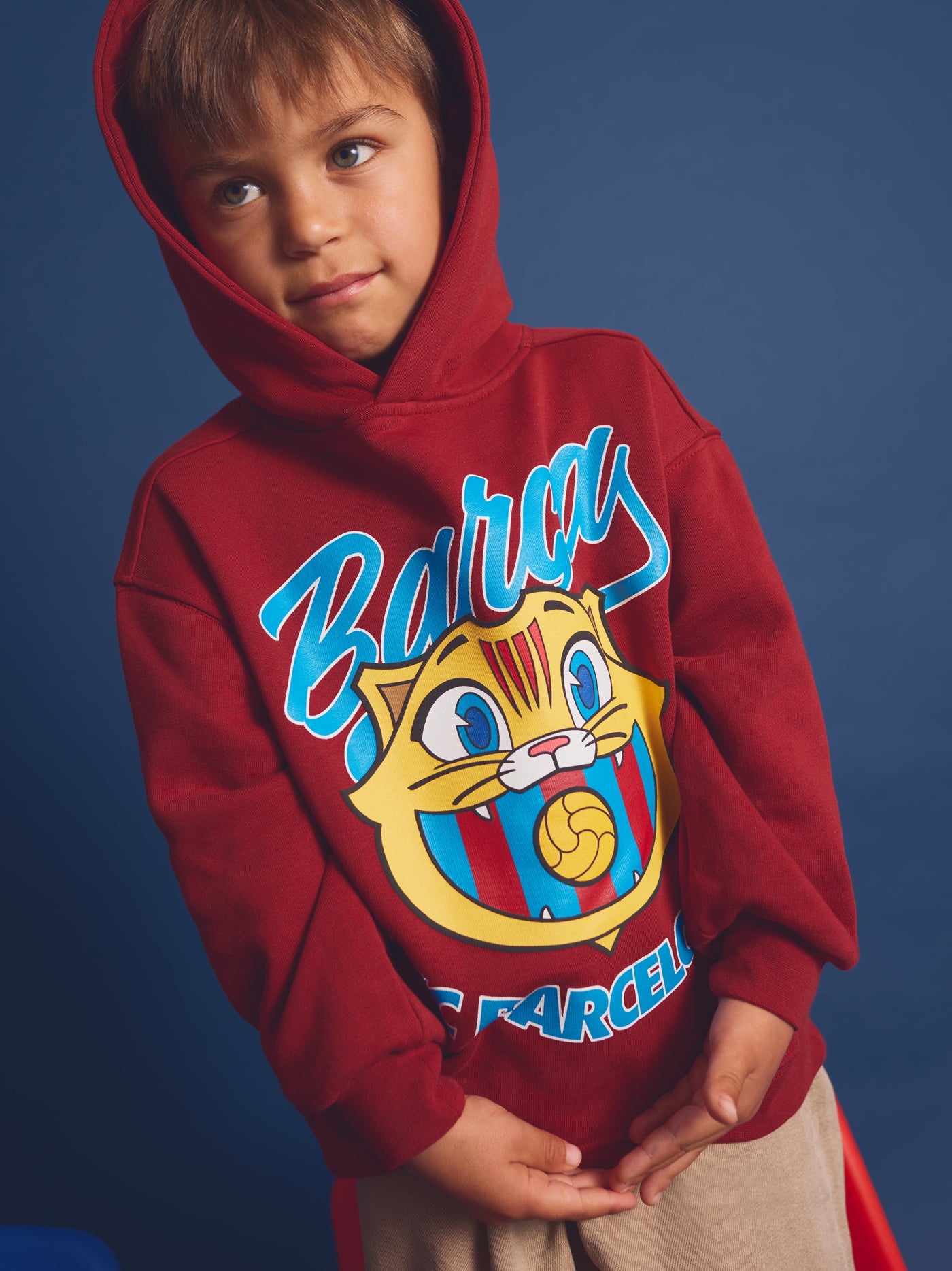 Child wearing a red FC Barcelona hoodie with the text 'Barça' and a cartoon illustration of Cat Culer, the club's mascot, on the front.