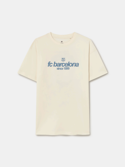 Off-white T-shirt featuring an illustrated graphic of Lamine Yamal with FC Barcelona elements and 'fc barcelona' text on the back.