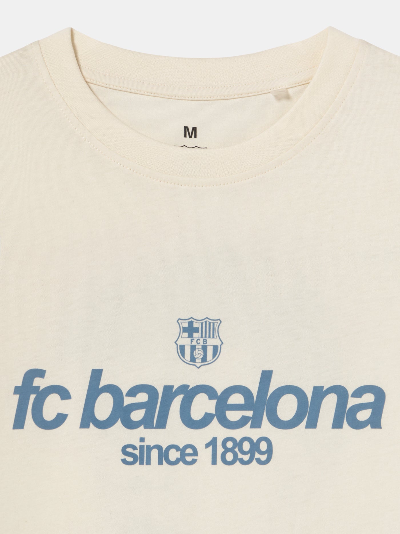 Off-white T-shirt featuring an illustrated graphic of Lamine Yamal with FC Barcelona elements and 'fc barcelona' text on the back.
