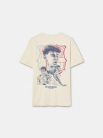 Beige FC Barcelona T-shirt featuring an artistic sketch-style print on the back of a male football player in various action poses. Behind the illustrations is the FC Barcelona crest outlined in red and blue. The design includes the text “fc barcelona since 1899” at the bottom.









