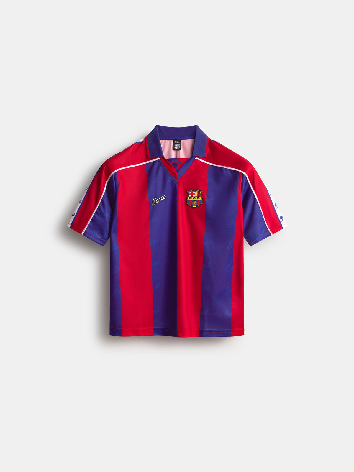 Vista frontal de una camiseta a rayas del FC Barcelona con cuello marino, paneles verticales rojos y azules, ribete blanco en los hombros y el escudo del club en el pecho.