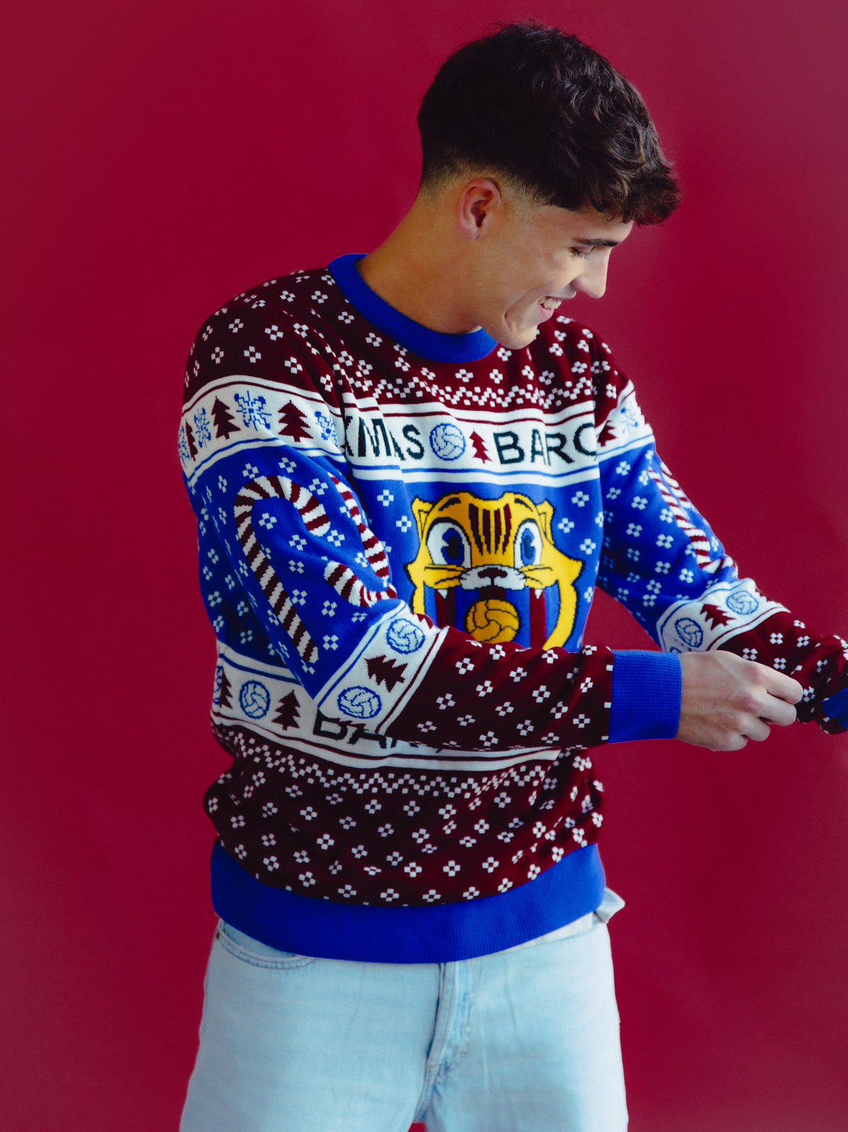 Vista frontal de un modelo con un jersey navideño de FC Barcelona con estampados nórdicos azules, burdeos y blancos y un gran motivo central del escudo del Barça.