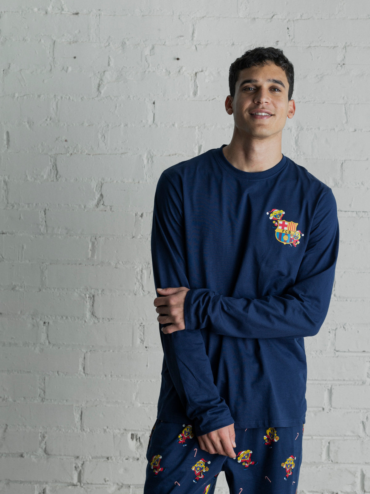 Modèle portant un haut à manches longues bleu marine FC Barcelona et un pantalon assorti avec un motif répété multicolore du blason du Barça.