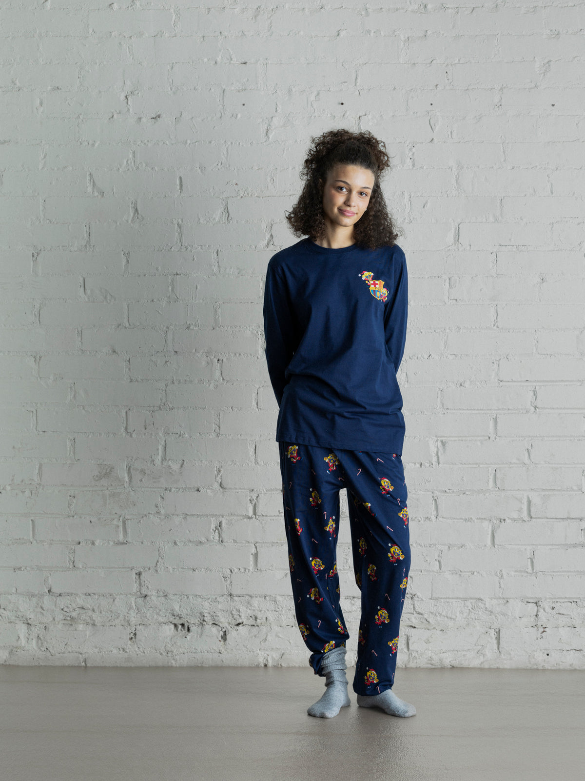 Modèle portant un haut à manches longues bleu marine FC Barcelona et un pantalon imprimé assorti, avec un petit blason Barça coloré sur la poitrine.
