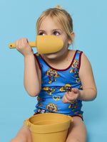 Child playing with a yellow shovel and bucket against a blue background