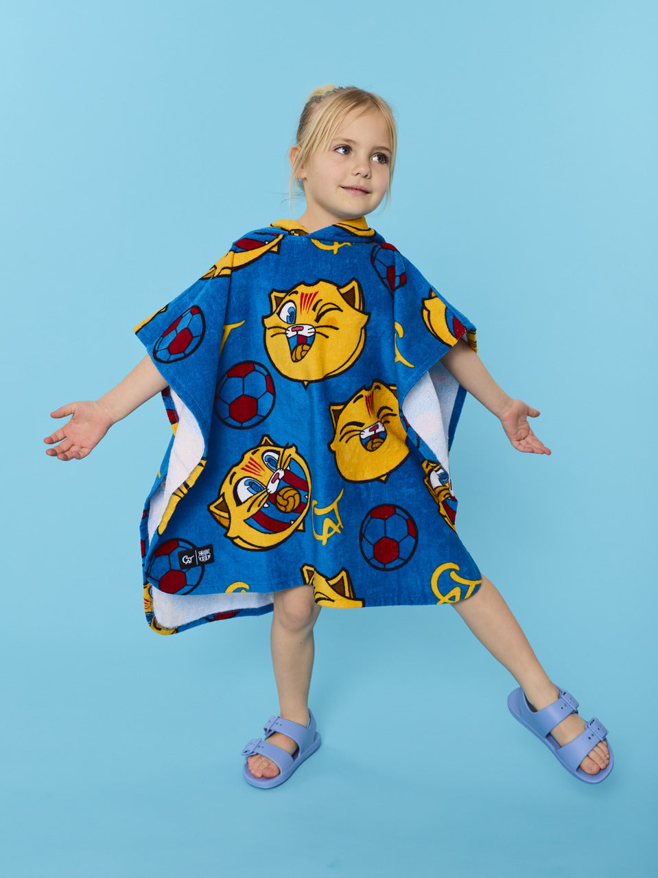 Child wearing a blue cartoon-themed poncho on a light blue background