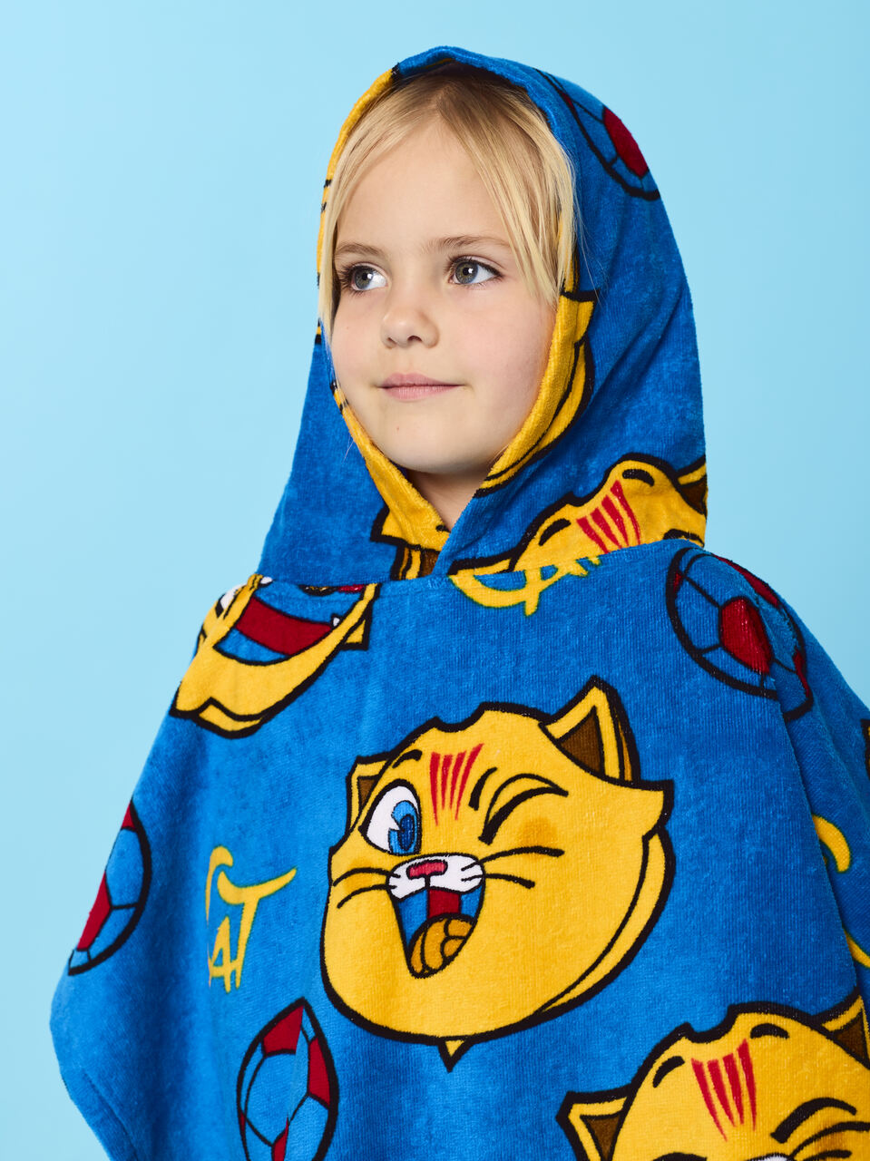 Child wearing a blue hooded towel with cartoon cat design on a light blue background