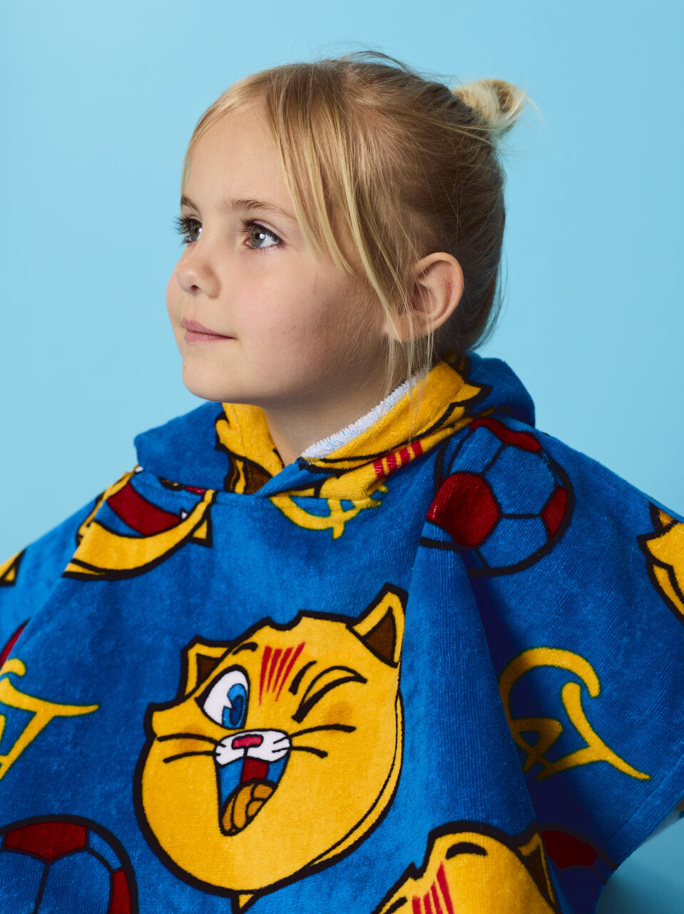 Child wearing a blue cape with cartoon cat design against a light blue background