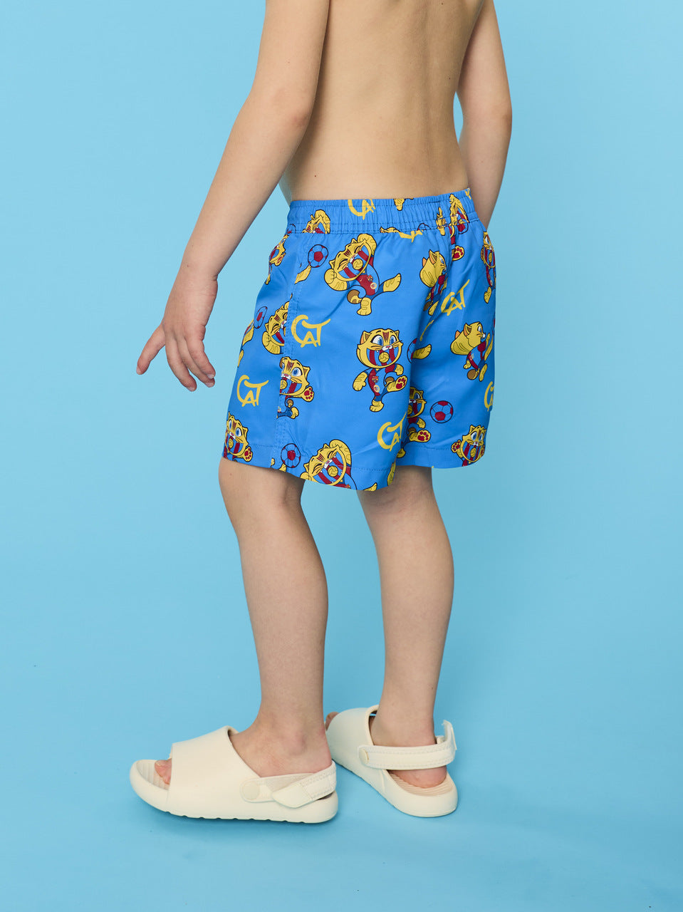 Child wearing blue swim shorts with cartoon character pattern on a blue background