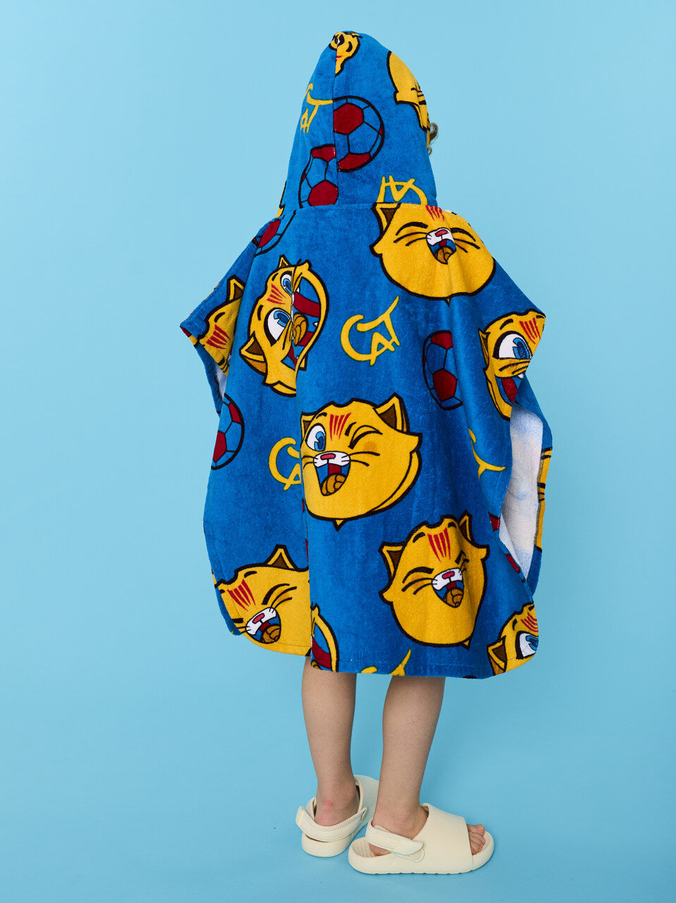 Child wearing a blue hooded towel with cartoon cat faces on a blue background