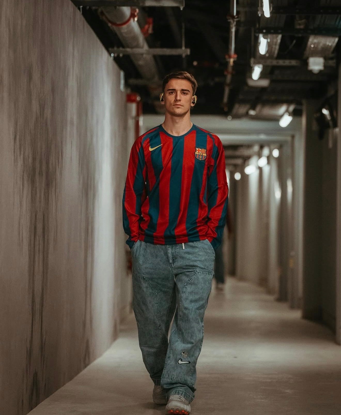 Person wearing a red and blue striped sweater in a long, narrow hallway.