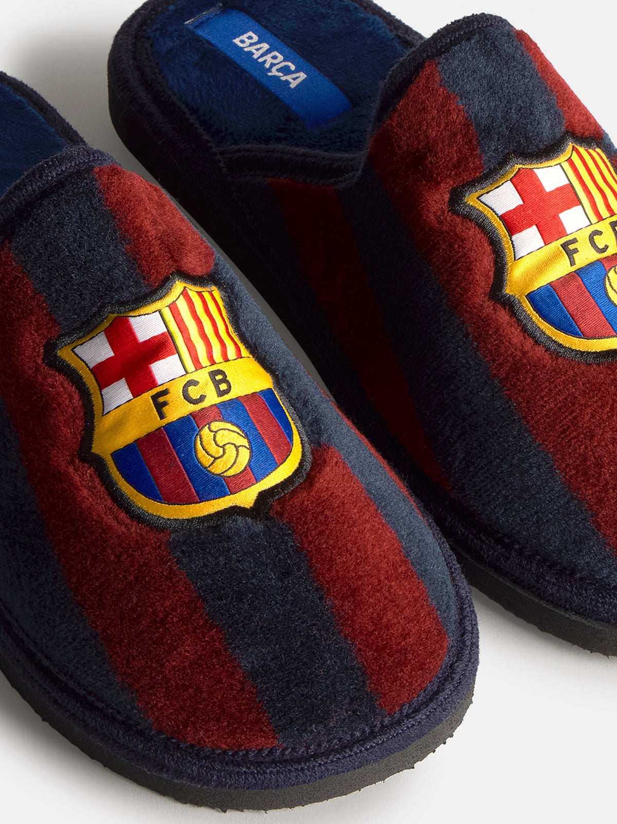 Paire de mules d’intérieur FC Barcelona avec des rayures bleu marine et grenat en peluche et un grand écusson du club sur le dessus.