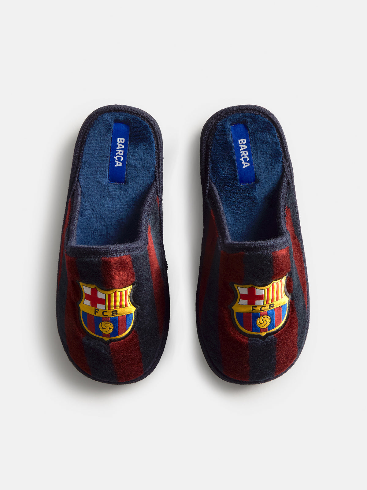 Paire de chaussons FC Barcelona à rayures bleu marine et bordeaux, vue de dessus avec l’écusson du Barça sur chaque bout et une étiquette bleue BARÇA à l’intérieur.
