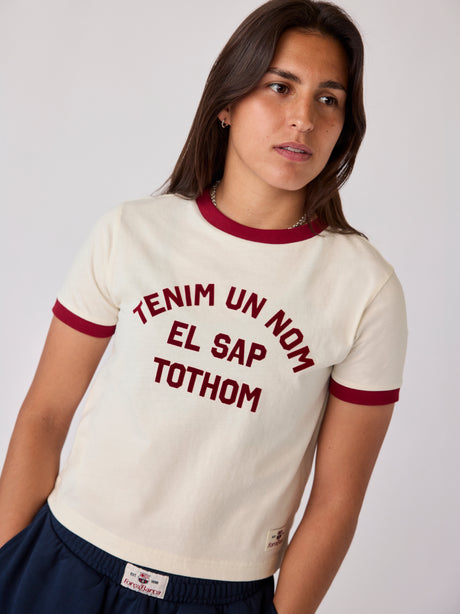 Model wearing a cream Barça T-shirt with burgundy trim and Catalan text graphic.