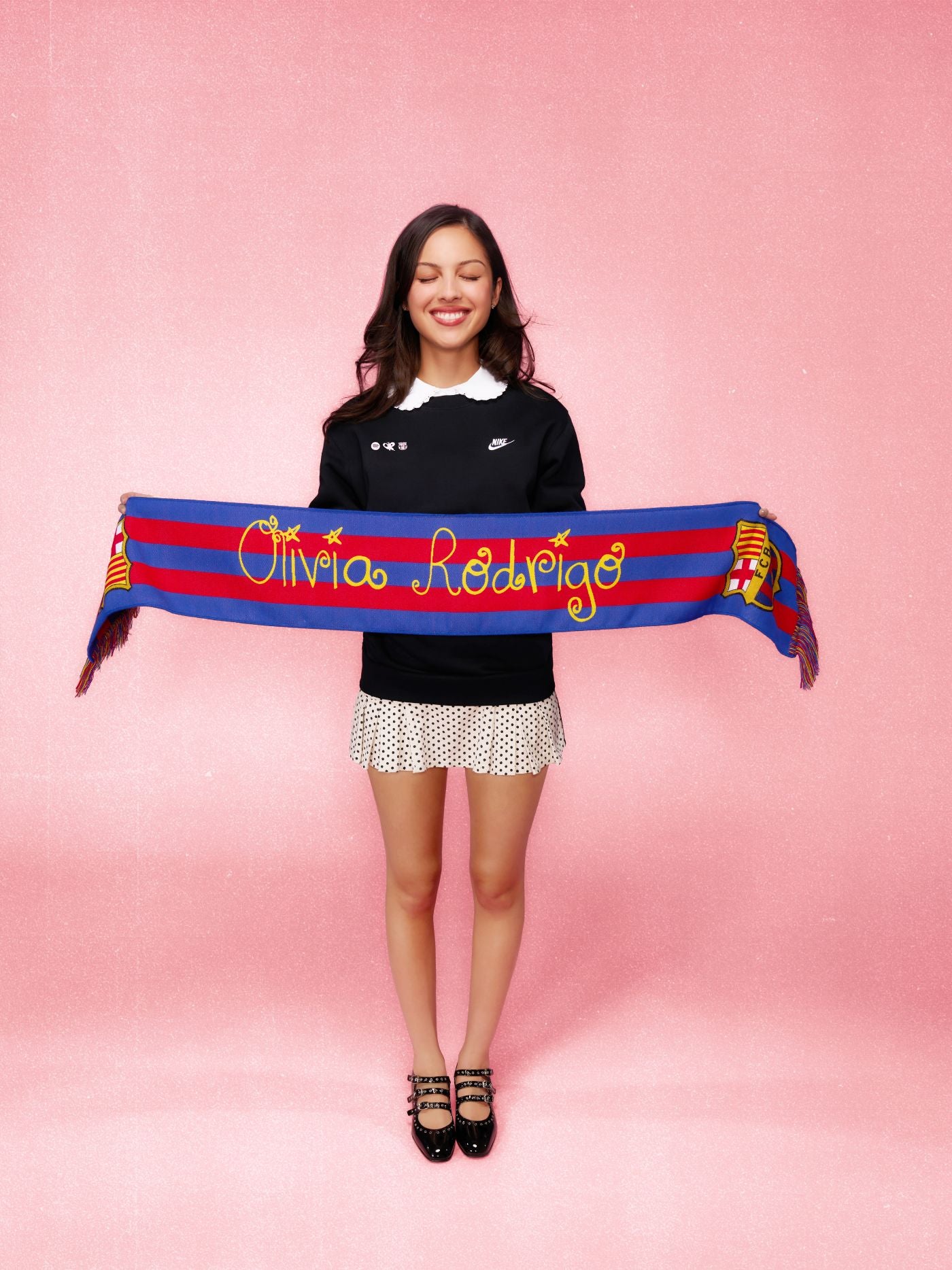 Woman holding a colorful scarf with text and logos on a pink background