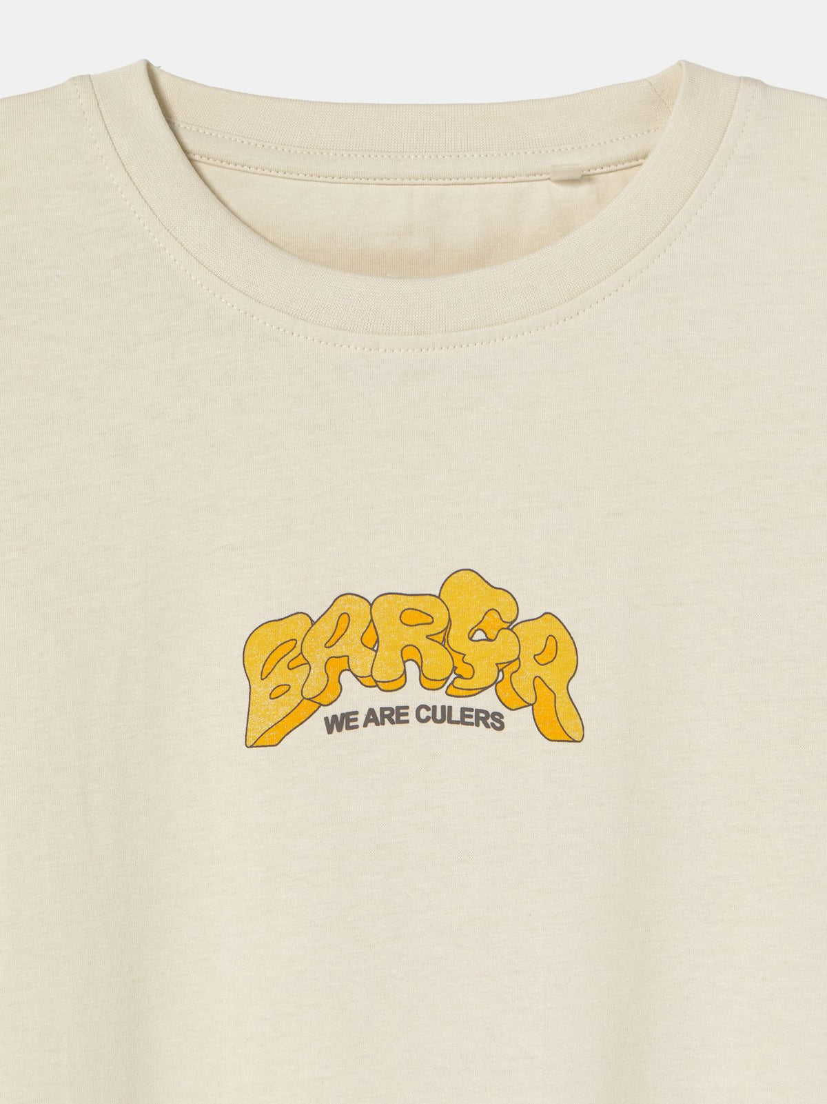 Beige FC Barcelona T-shirt featuring a vibrant vintage-style back print with the word "Barça" in large retro bubble letters. The graphic includes a football, flags, and stadium elements in bold colors within a shield-like frame. A ribbon below the design reads “Since 1899” and “Més que un club.”