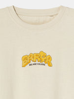 Beige FC Barcelona T-shirt featuring a vibrant vintage-style back print with the word "Barça" in large retro bubble letters. The graphic includes a football, flags, and stadium elements in bold colors within a shield-like frame. A ribbon below the design reads “Since 1899” and “Més que un club.”