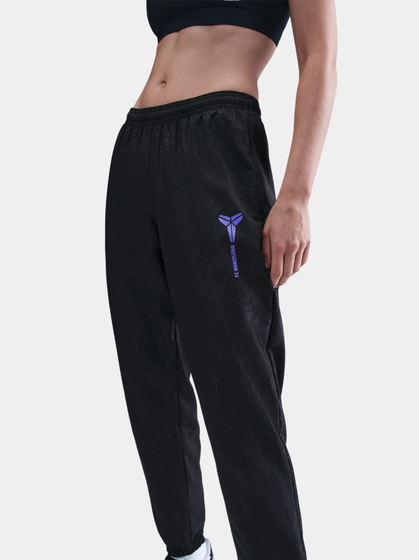 Black FC Barcelona training pants featuring the Kobe Bryant logo and 'FC Barcelona' text in purple on the right thigh.