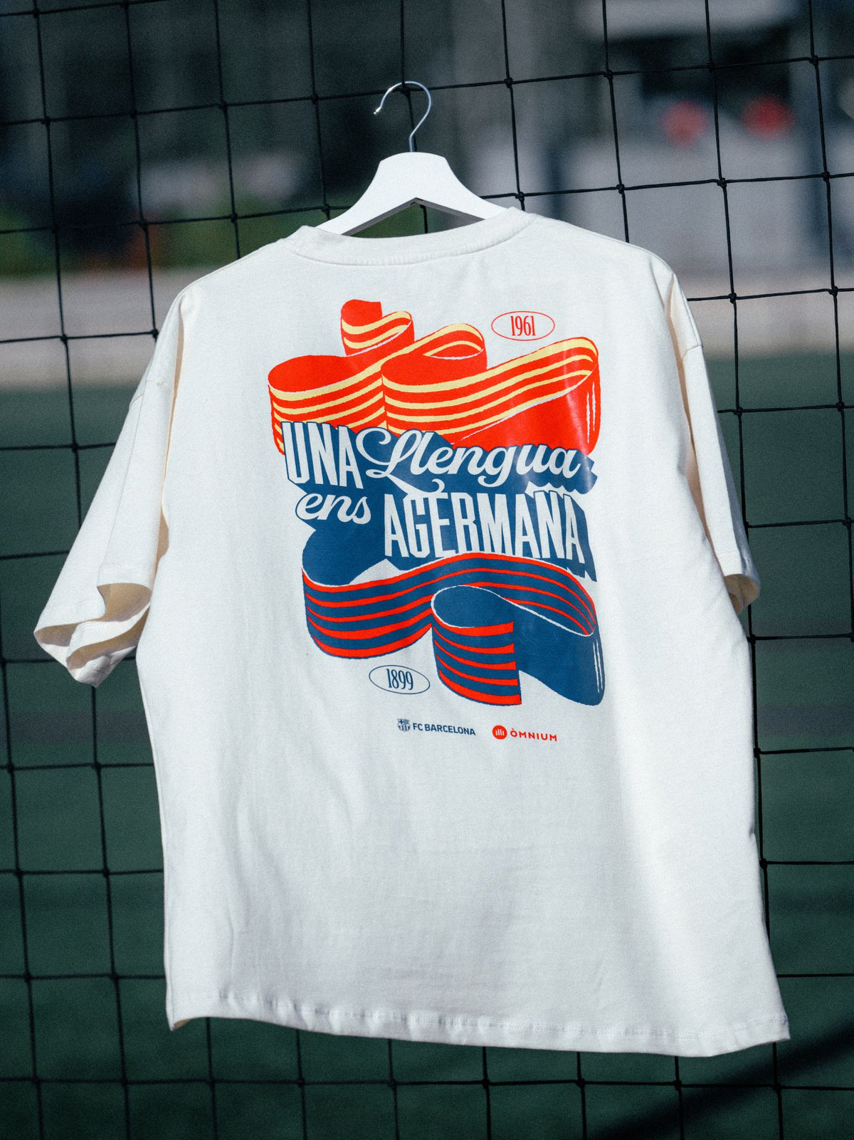White t-shirt with colorful graphic design on a hanger against a grid background