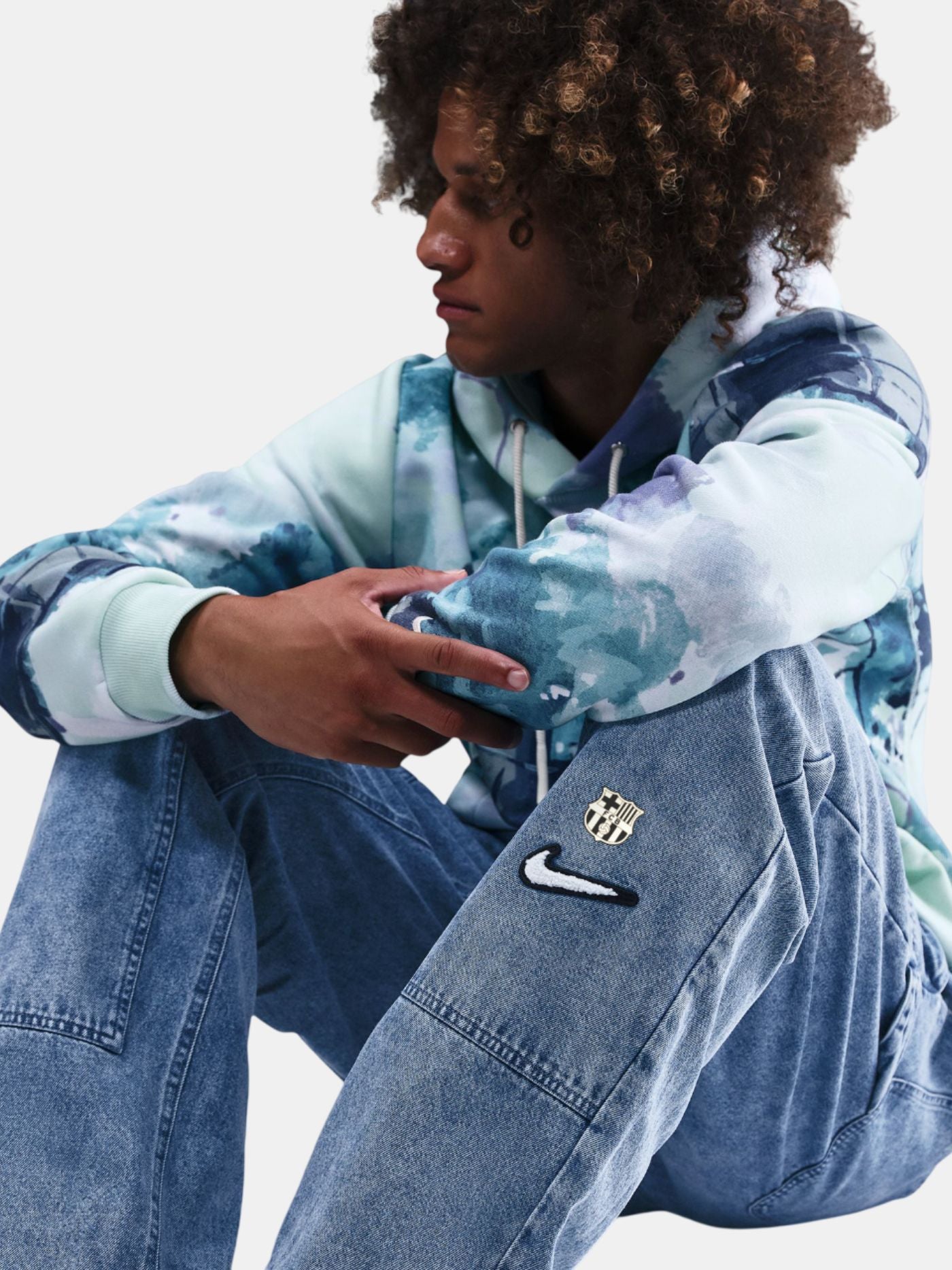 Person wearing a blue and white tie-dye hoodie with a logo on a light gray background