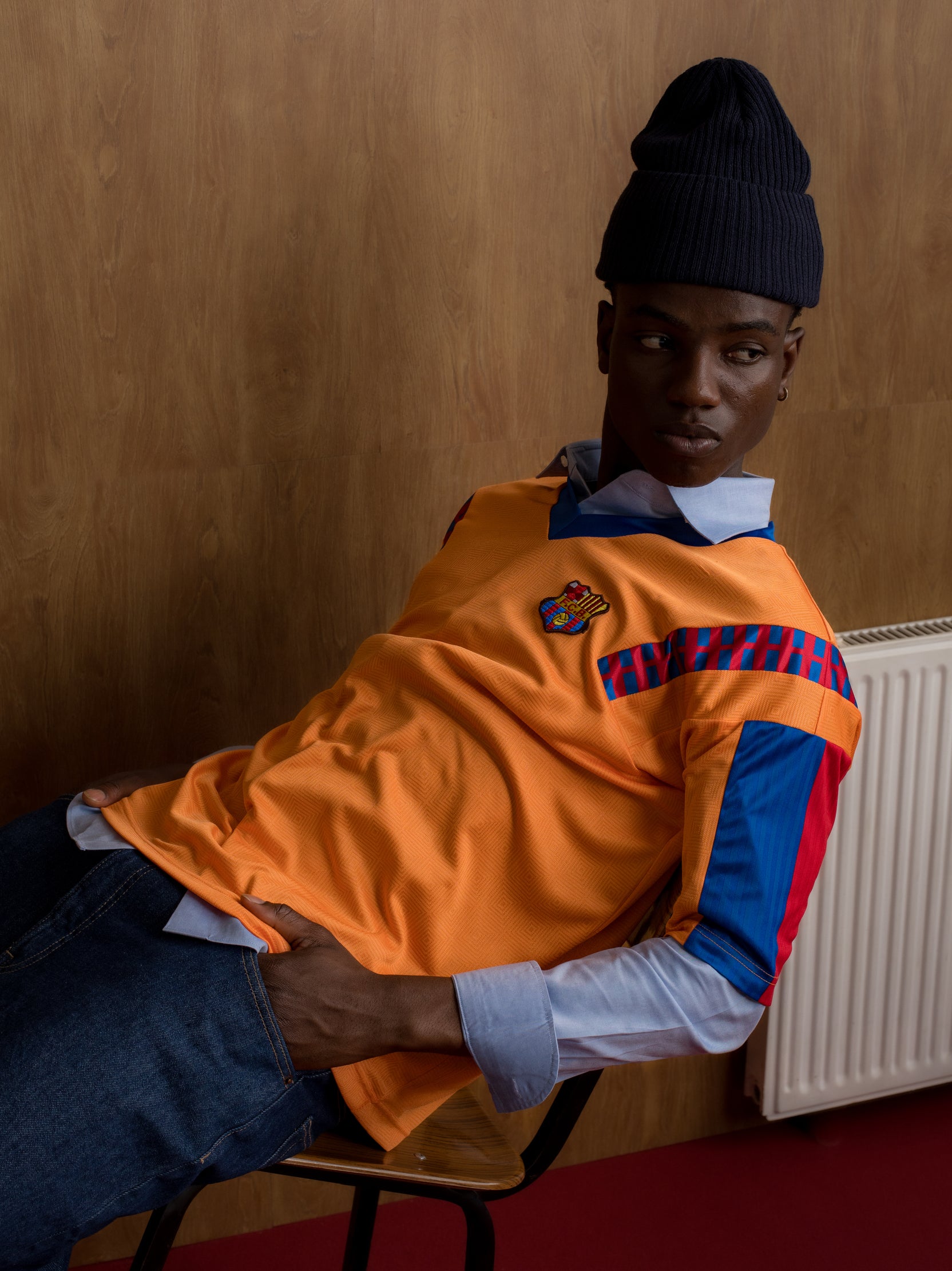 Orange retro-style FC Barcelona jersey with crest on the chest and red and blue details on the sleeves and shoulders.