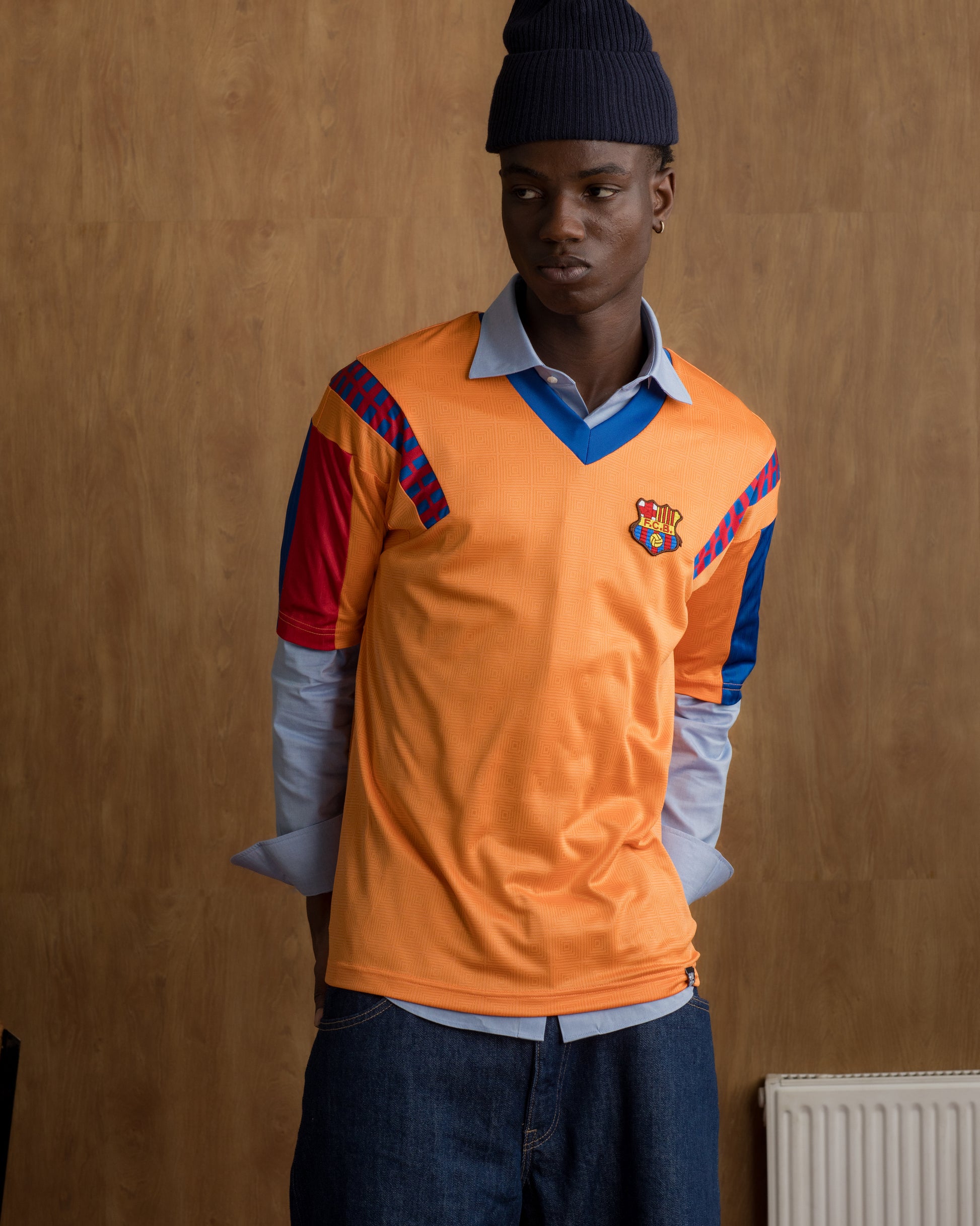 Orange retro-style FC Barcelona jersey with crest on the chest and red and blue details on the sleeves and shoulders.